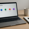 Moderner Arbeitsplatz mit Laptop, auf dem Microsoft 365 geöffnet ist, daneben Notizblock, Stift und Kaffeetasse auf hellem Schreibtisch.